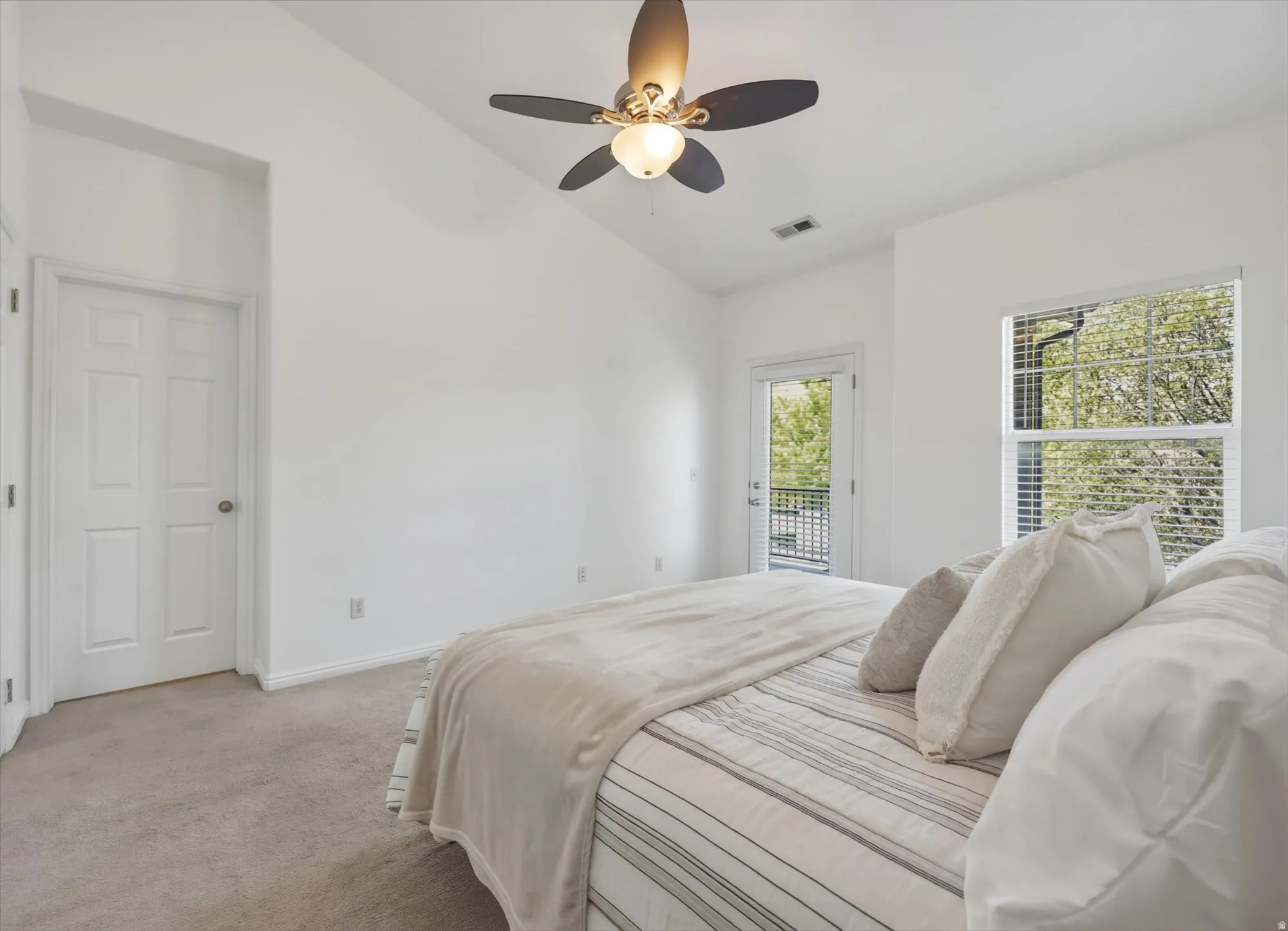 Bedroom featuring a vaulted ceiling with a ceiling fan, white paneled door, and carpet flooring