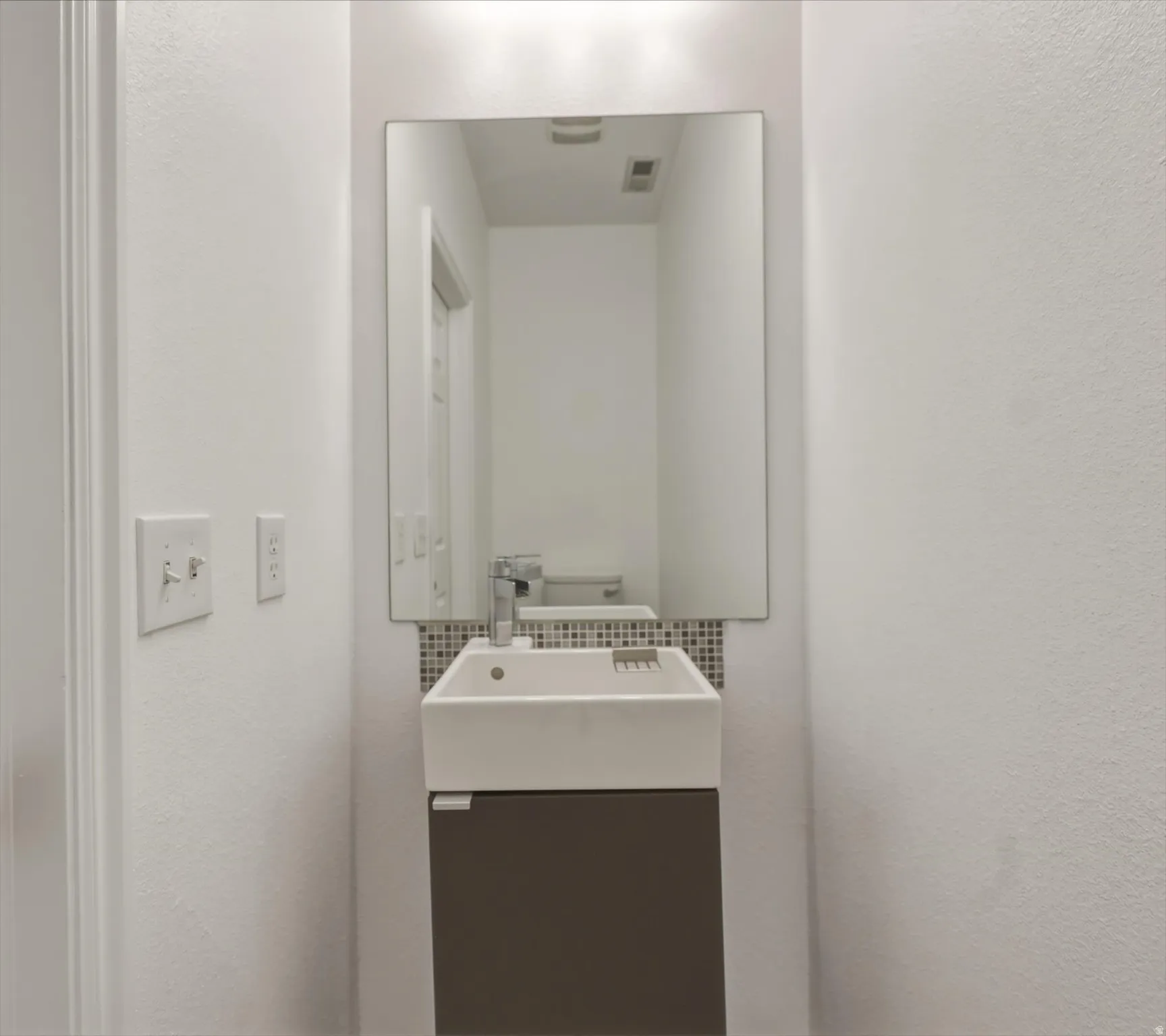 Wall-mounted floating vanity with an integrated rectangular sink and chrome faucet