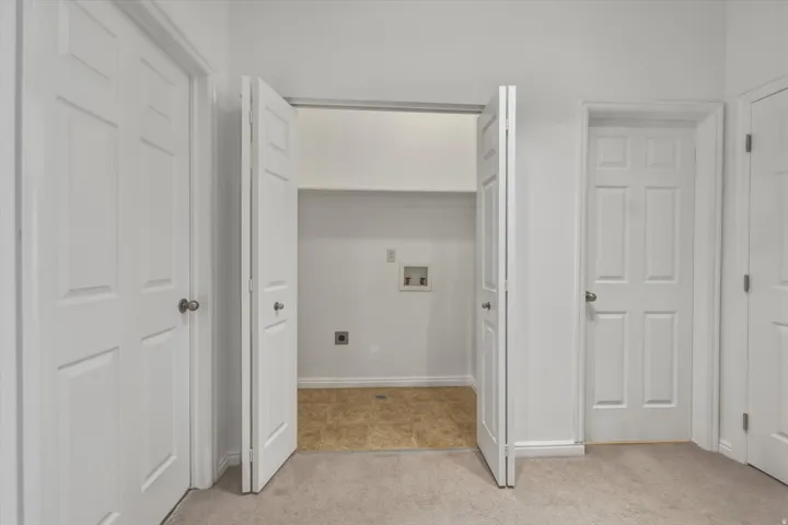 Dedicated laundry alcove with bi-fold doors, utility hookups, and durable flooring
