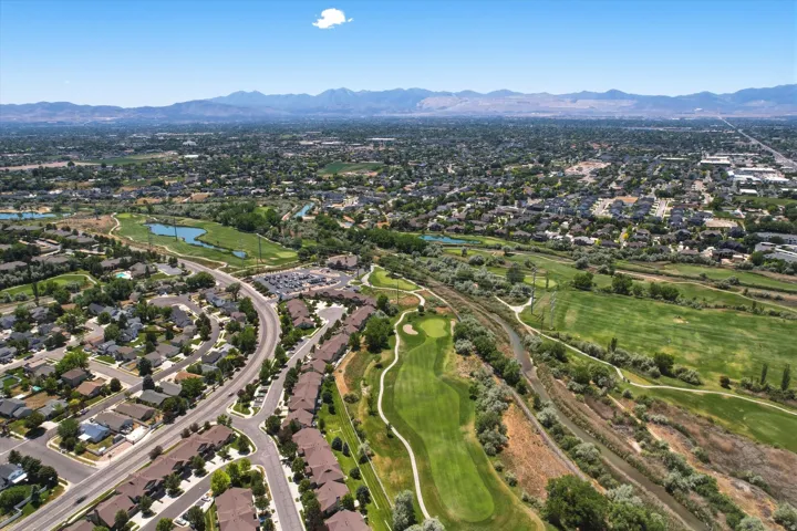 Aerial perspective showcasing a residential area with varied housing styles, bordered by extensive green spaces and a golf course