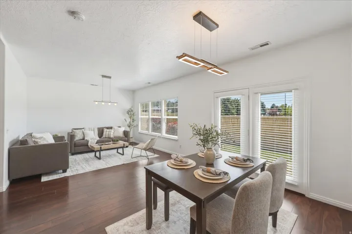 Open-concept living and dining areas featuring dark wood-finish flooring, white walls, and recessed lighting