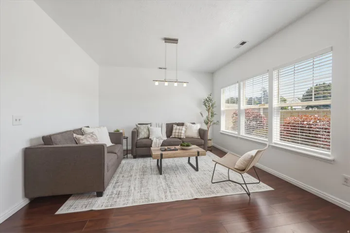 Spacious room featuring rich wood-finish flooring, a vaulted ceiling, and ample natural light from three large windows