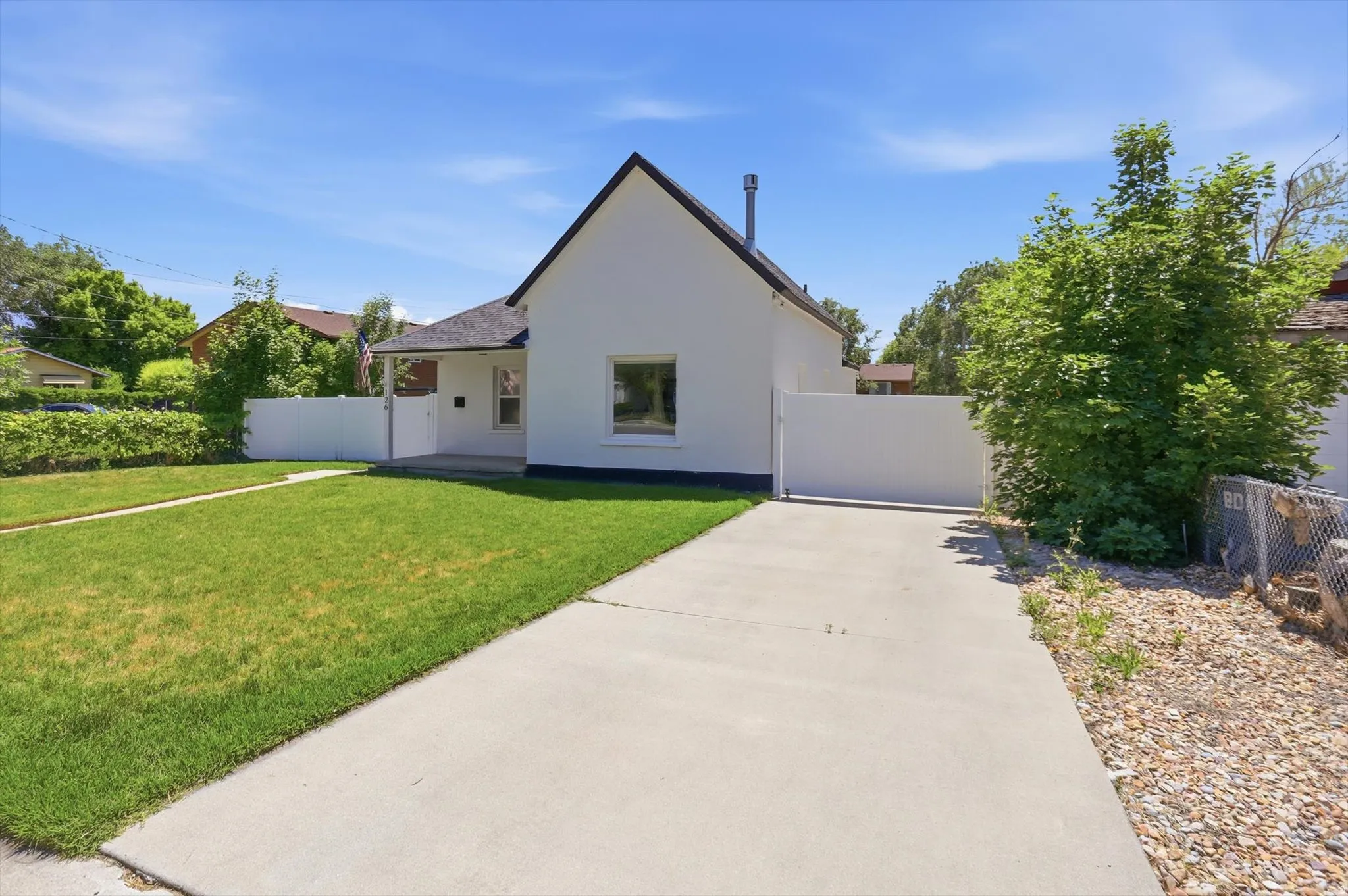 Crisp white exterior with a contrasting dark roofline, featuring a covered porch entry and a prominent front window