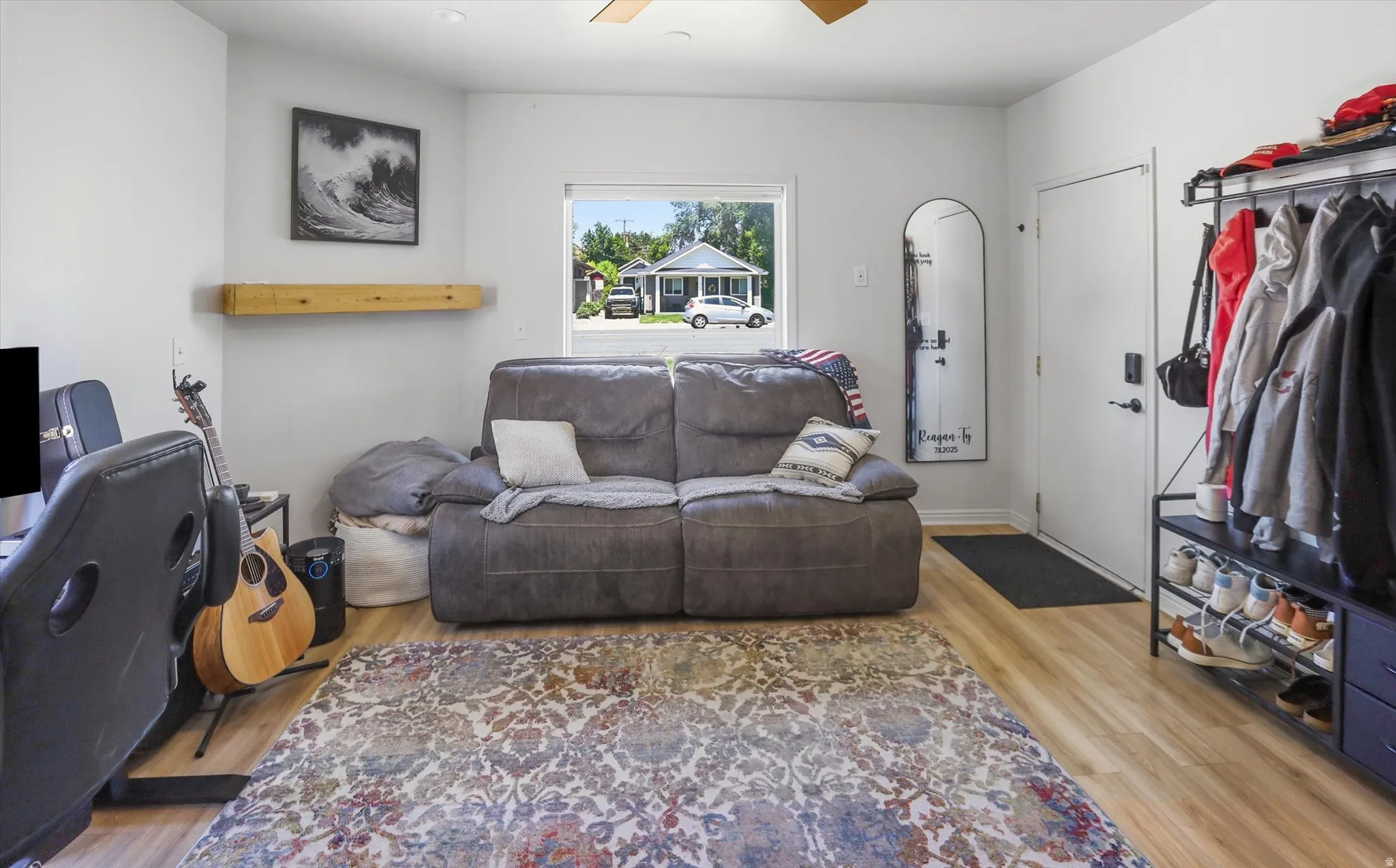 Bright interior space featuring wood-finish flooring, a white entry door, and a prominent window