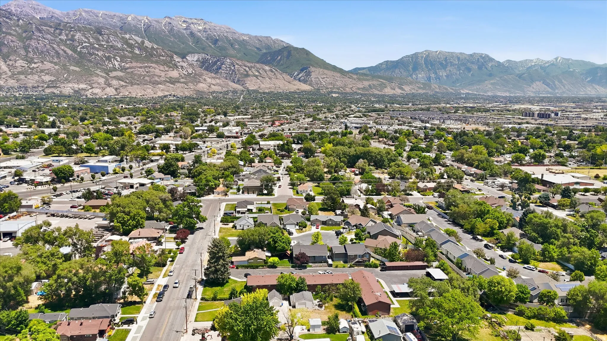 Expansive aerial perspective showcasing a residential area with mature tree coverage and distant mountainous terrain