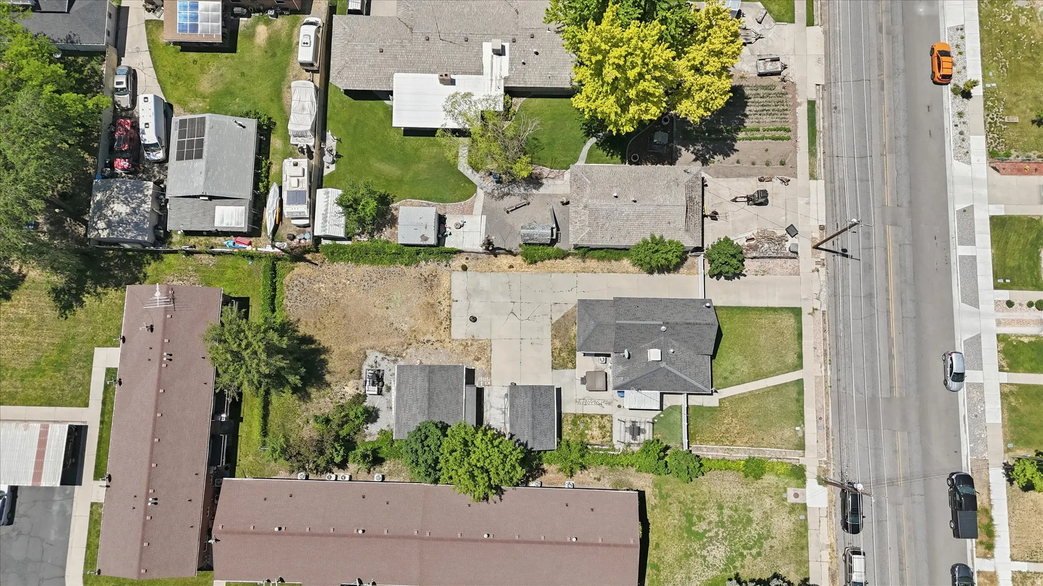 Aerial perspective showcasing multiple properties, extensive paved areas, and varied land parcels