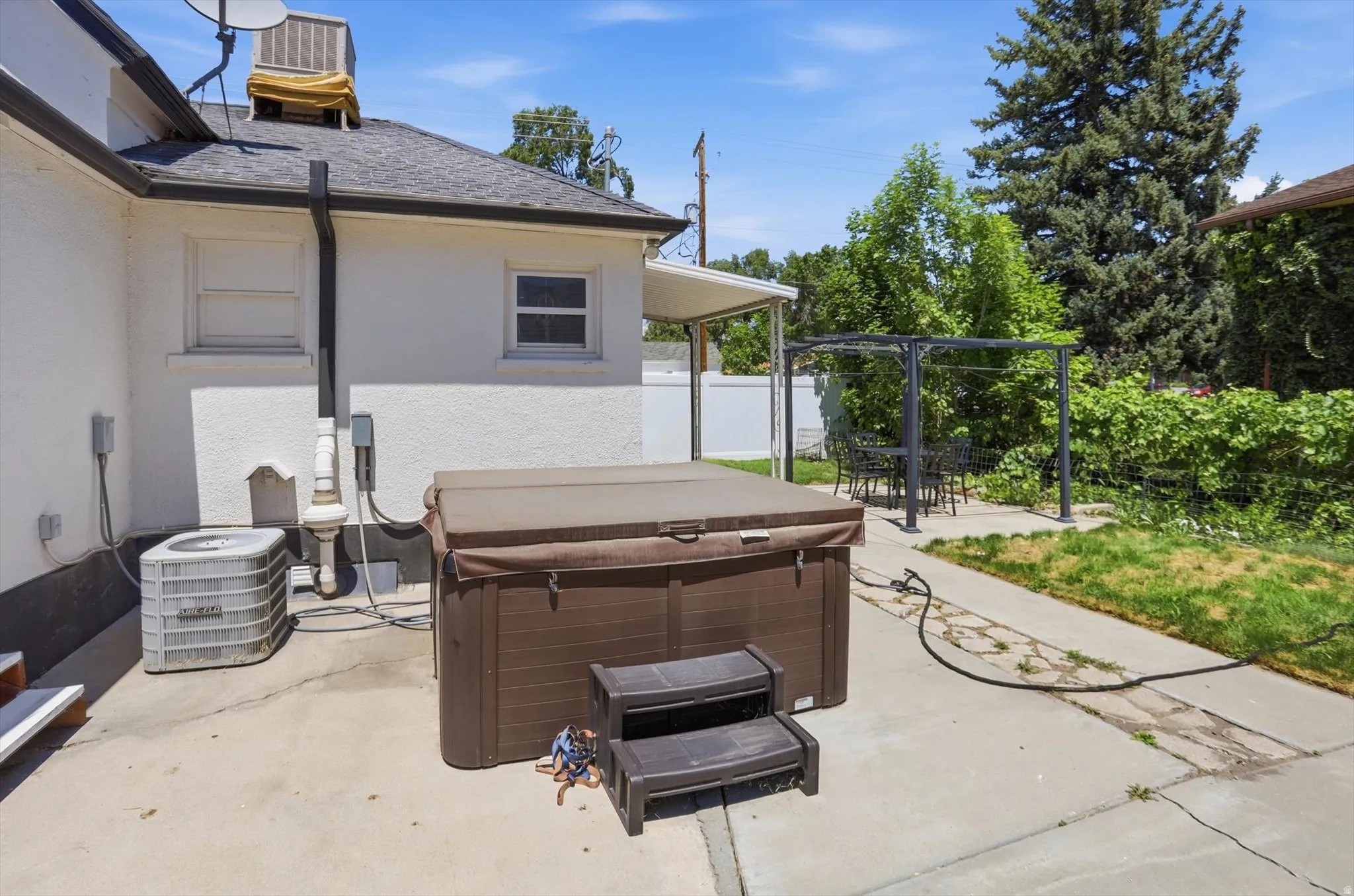 Rear patio with a built-in spa, concrete surfacing, and a covered area