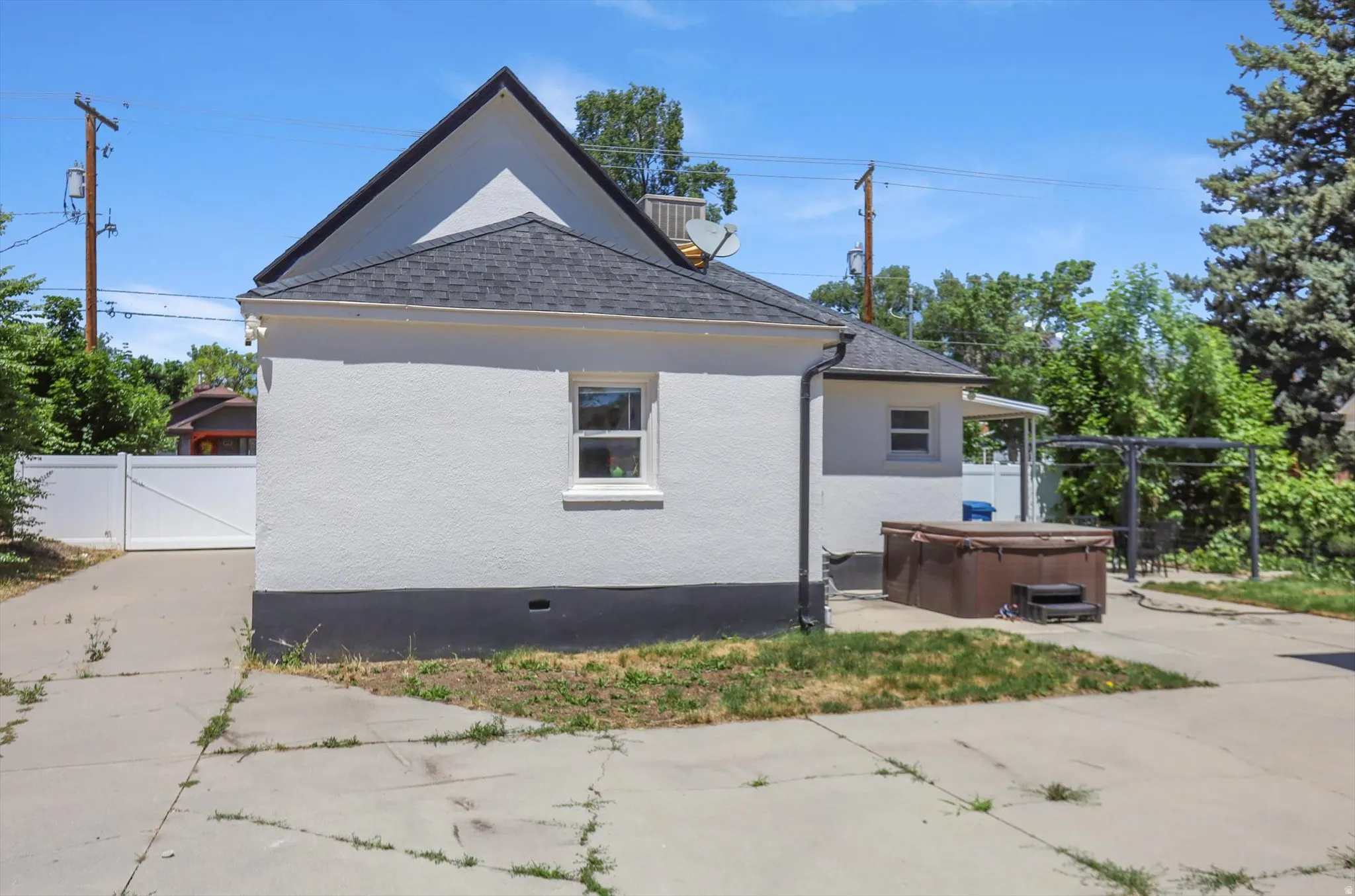 Exterior featuring white stucco siding with a dark foundation, a dark shingle roof, and white window trim