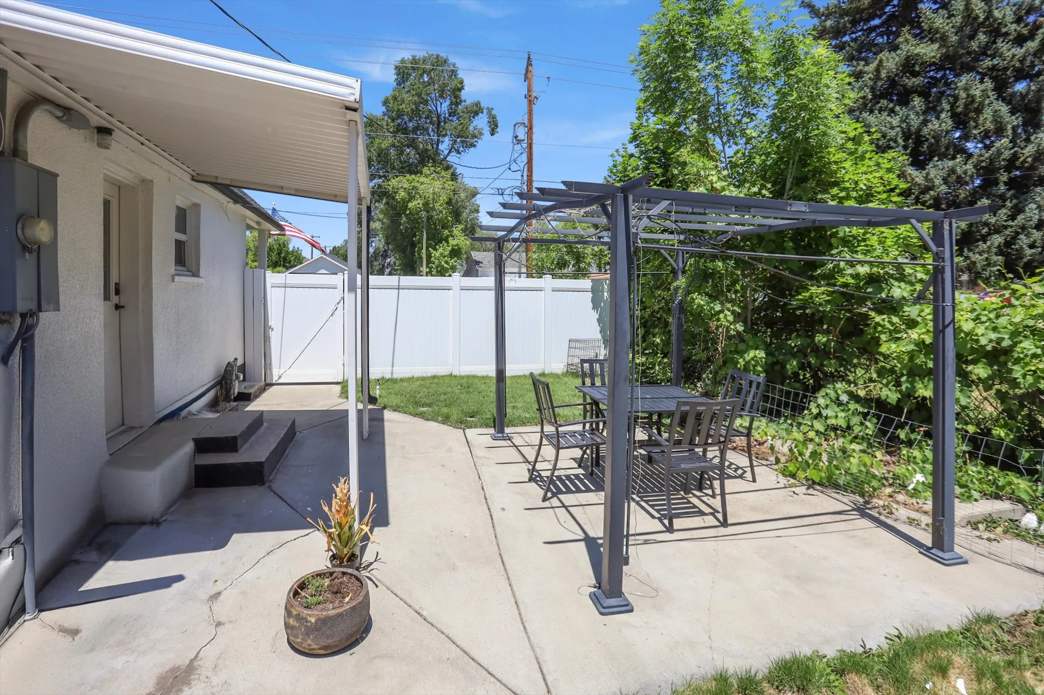 Expansive concrete patio featuring an attached pergola and a covered walkway