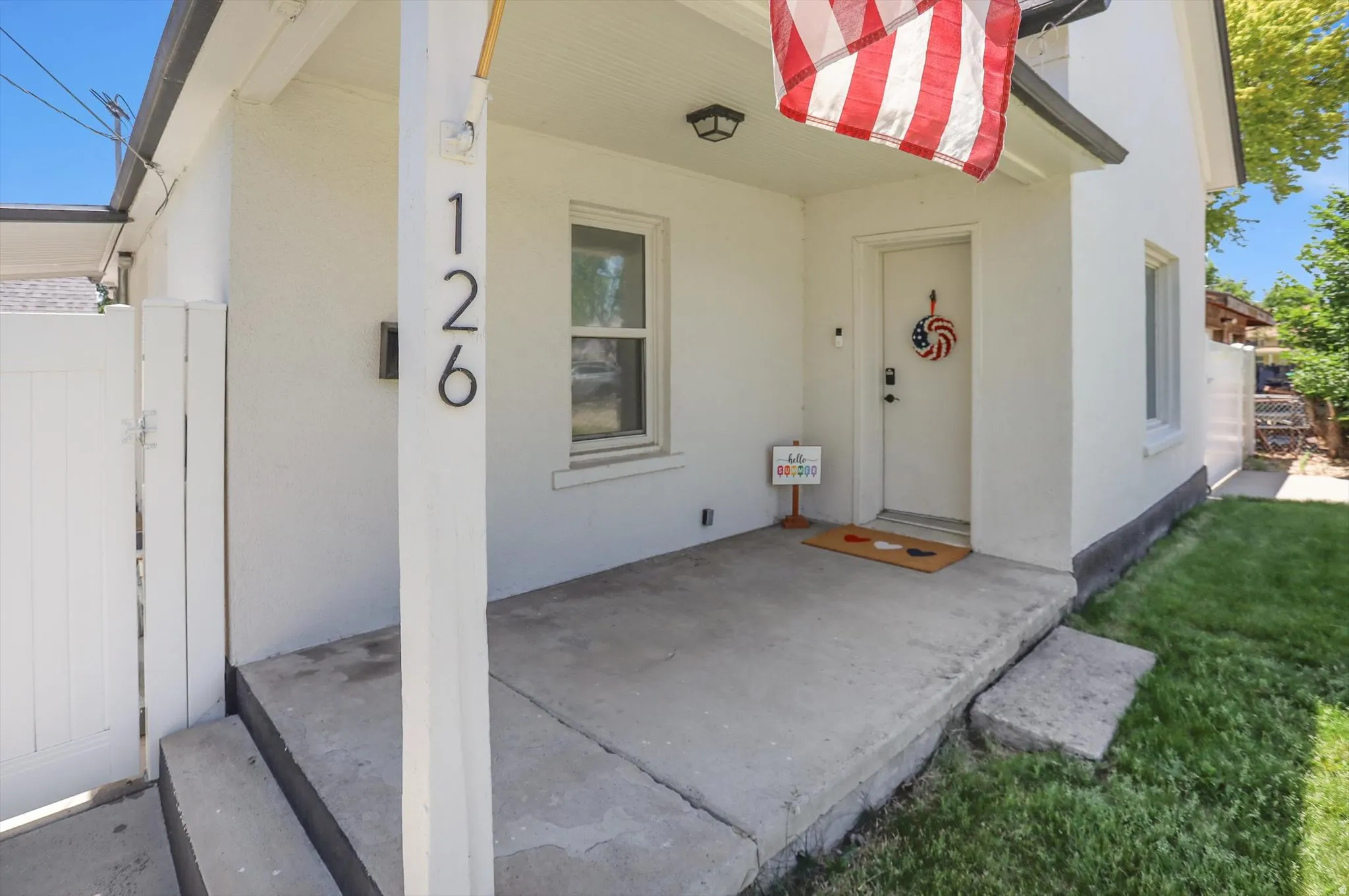 Inviting front porch featuring a sturdy support column, overhead lighting, and a white entry door