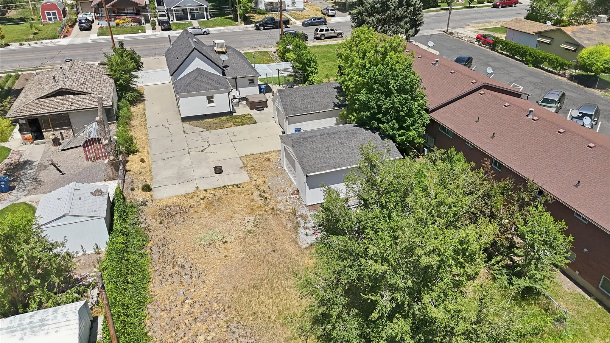 Expansive lot featuring a large concrete driveway, two detached garages, and mature trees