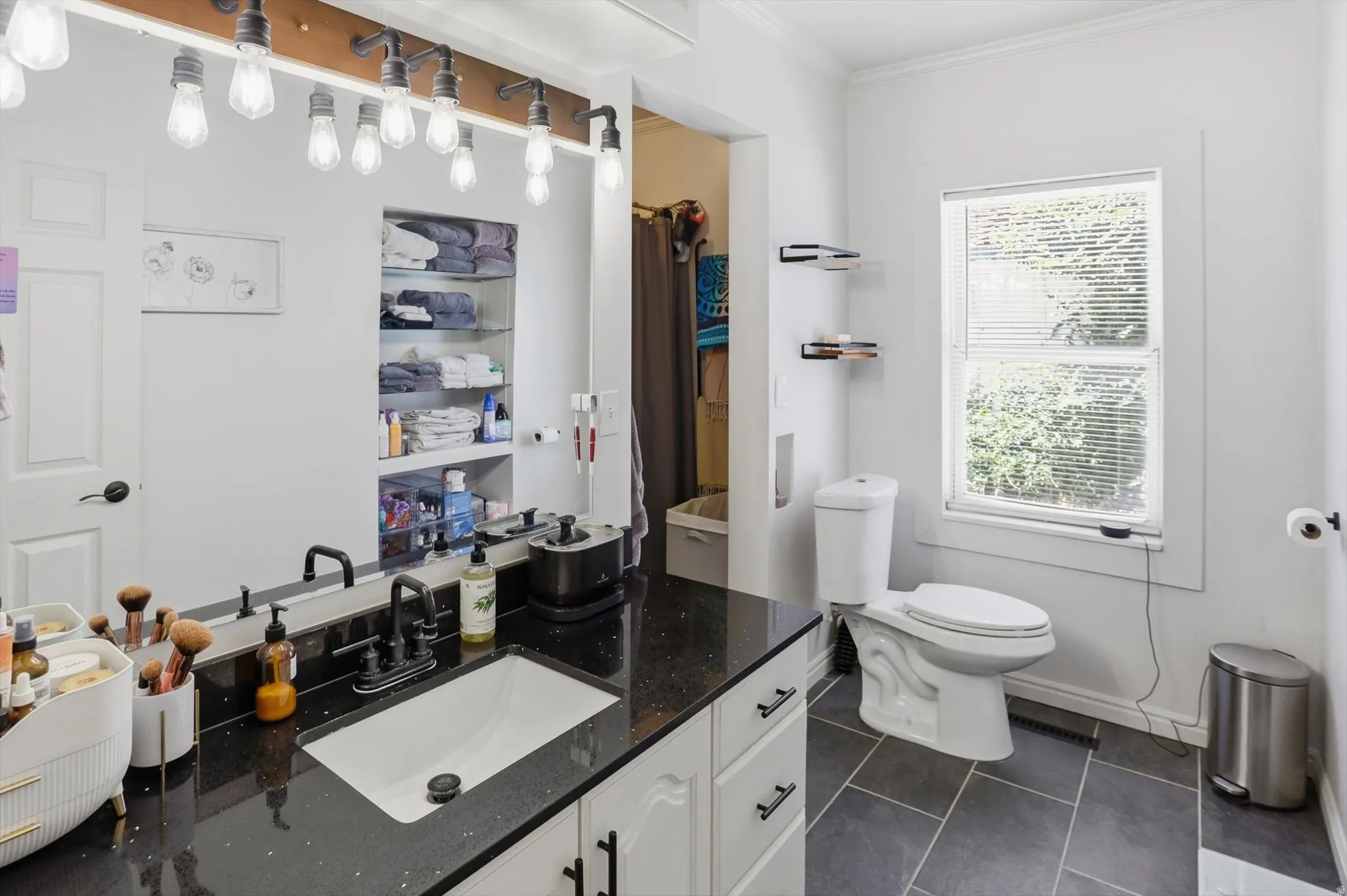 Bathroom featuring a single vanity with a black countertop, integrated sink, and matte black faucet