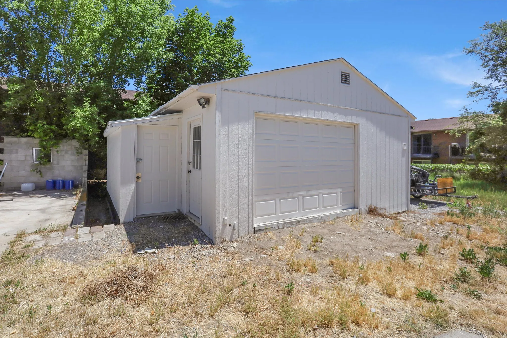 Detached garage structure featuring a single garage door, an exterior entrance door, and a covered side entry
