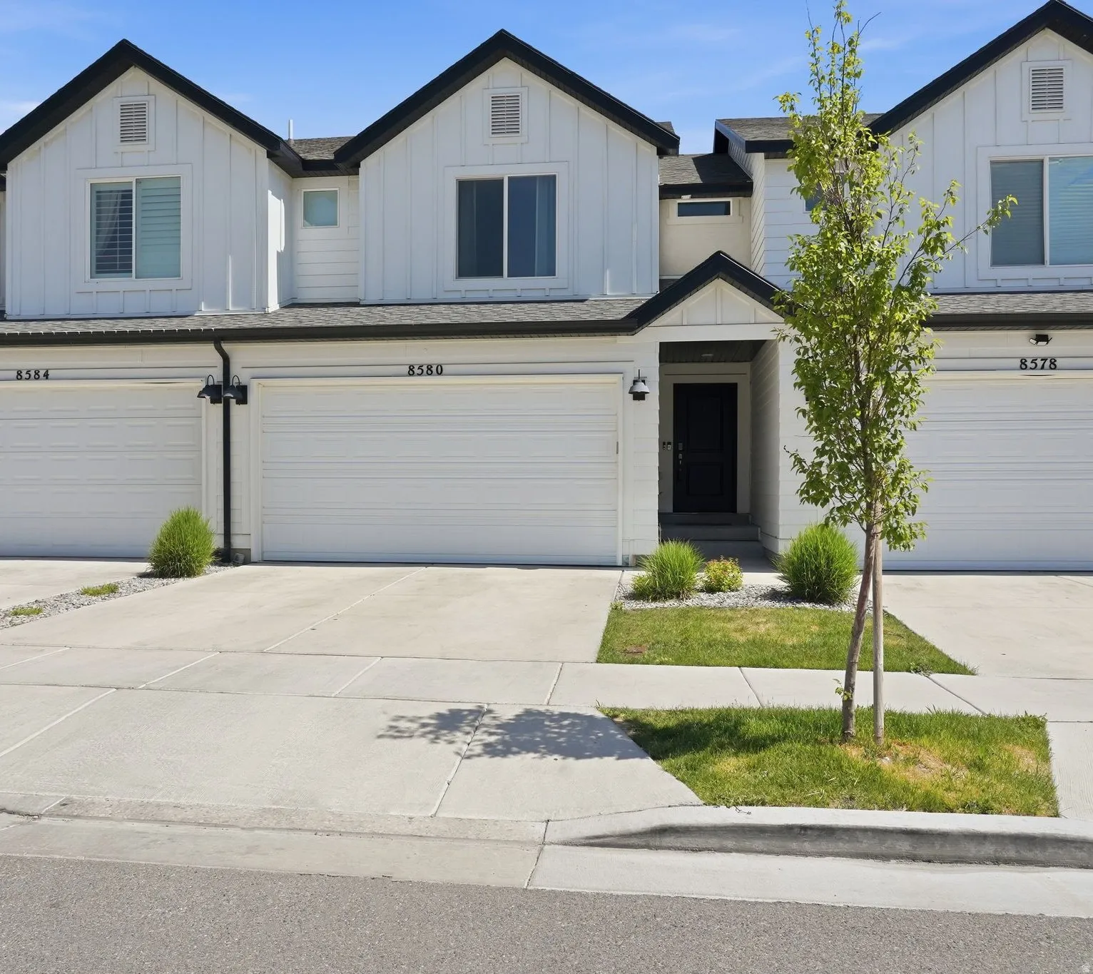 Modern farmhouse style townhouse exterior featuring white vertical siding with dark trim accents