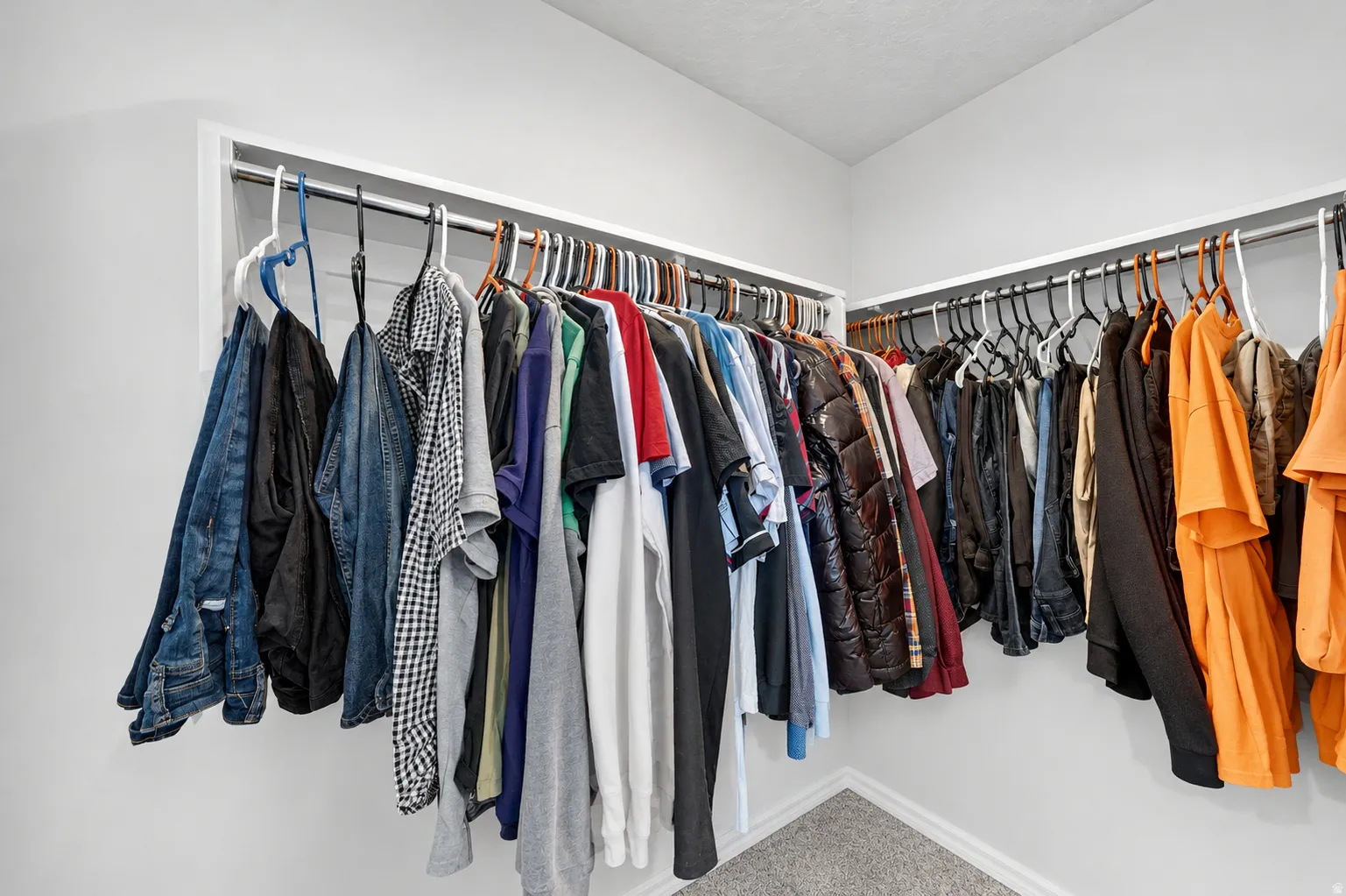 Walk-in closet featuring extensive hanging space, white walls, and gray carpet flooring