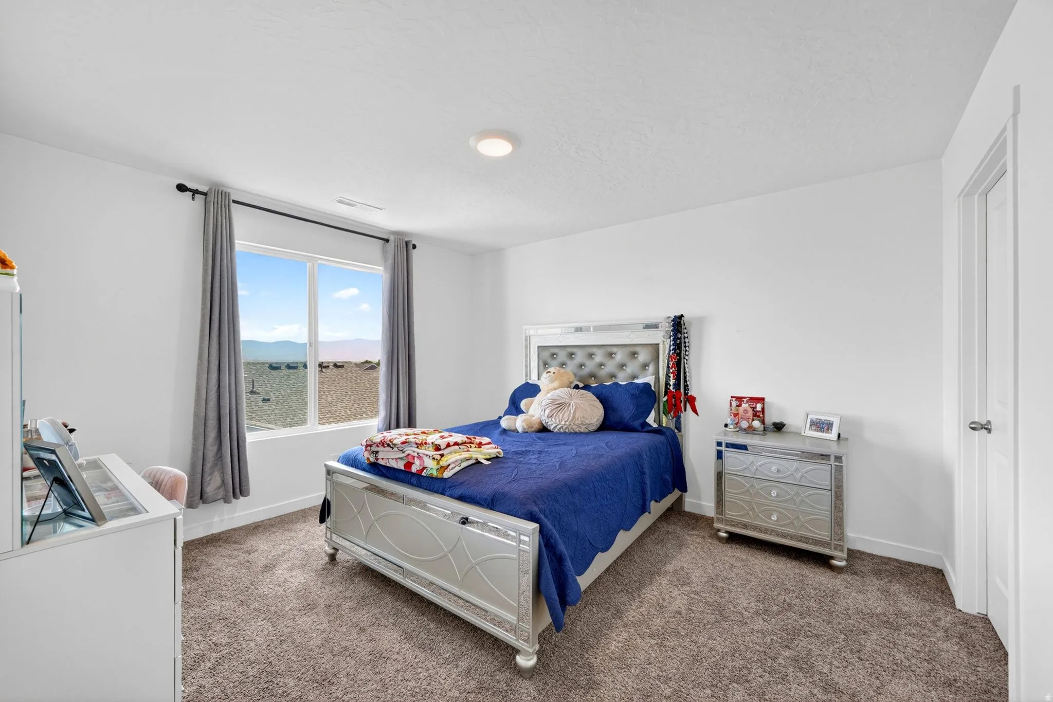 Bedroom featuring a large window, textured carpet, white walls, and a recessed ceiling light