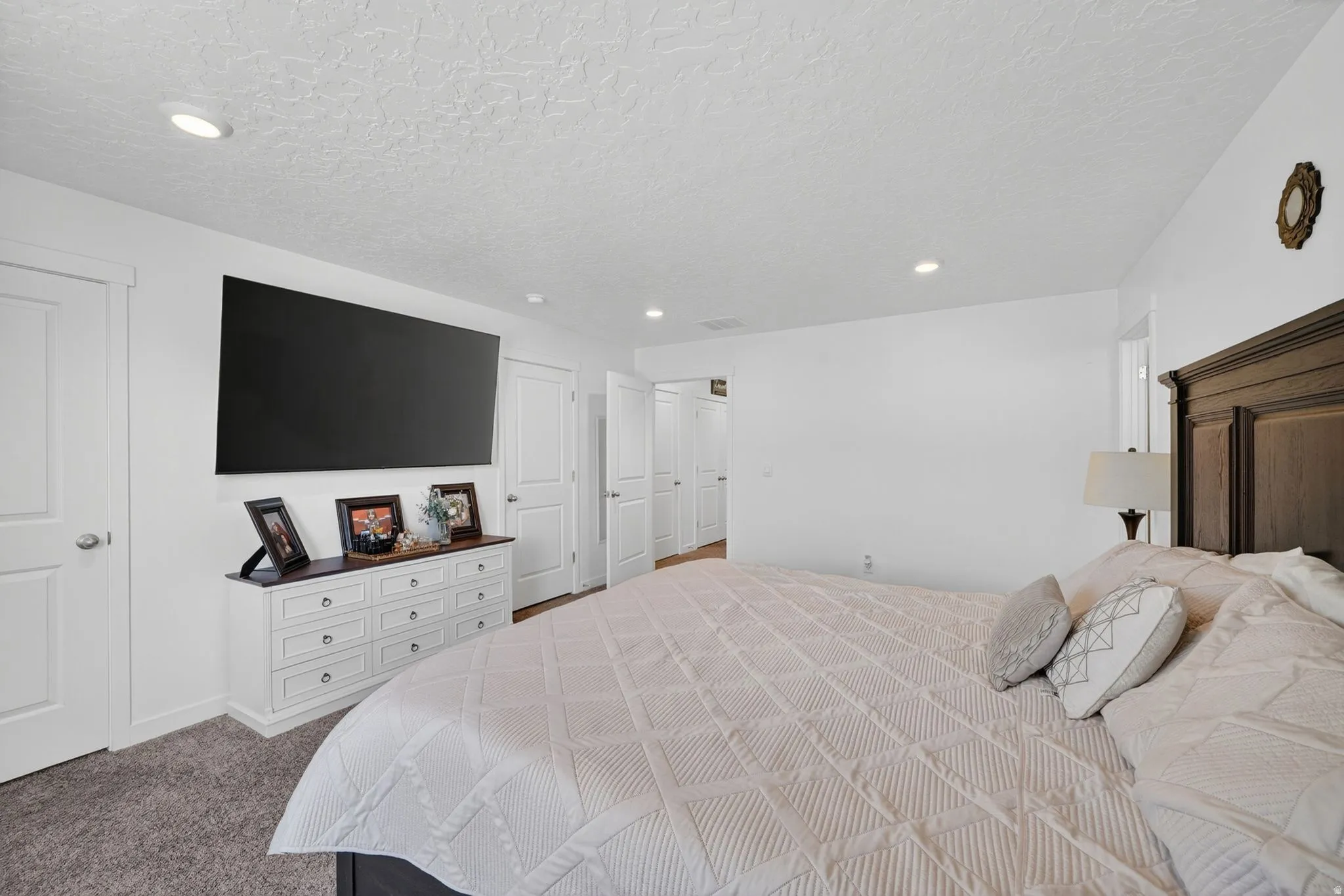 Carpeted bedroom featuring white walls, recessed ceiling lighting, and multiple white panel doors