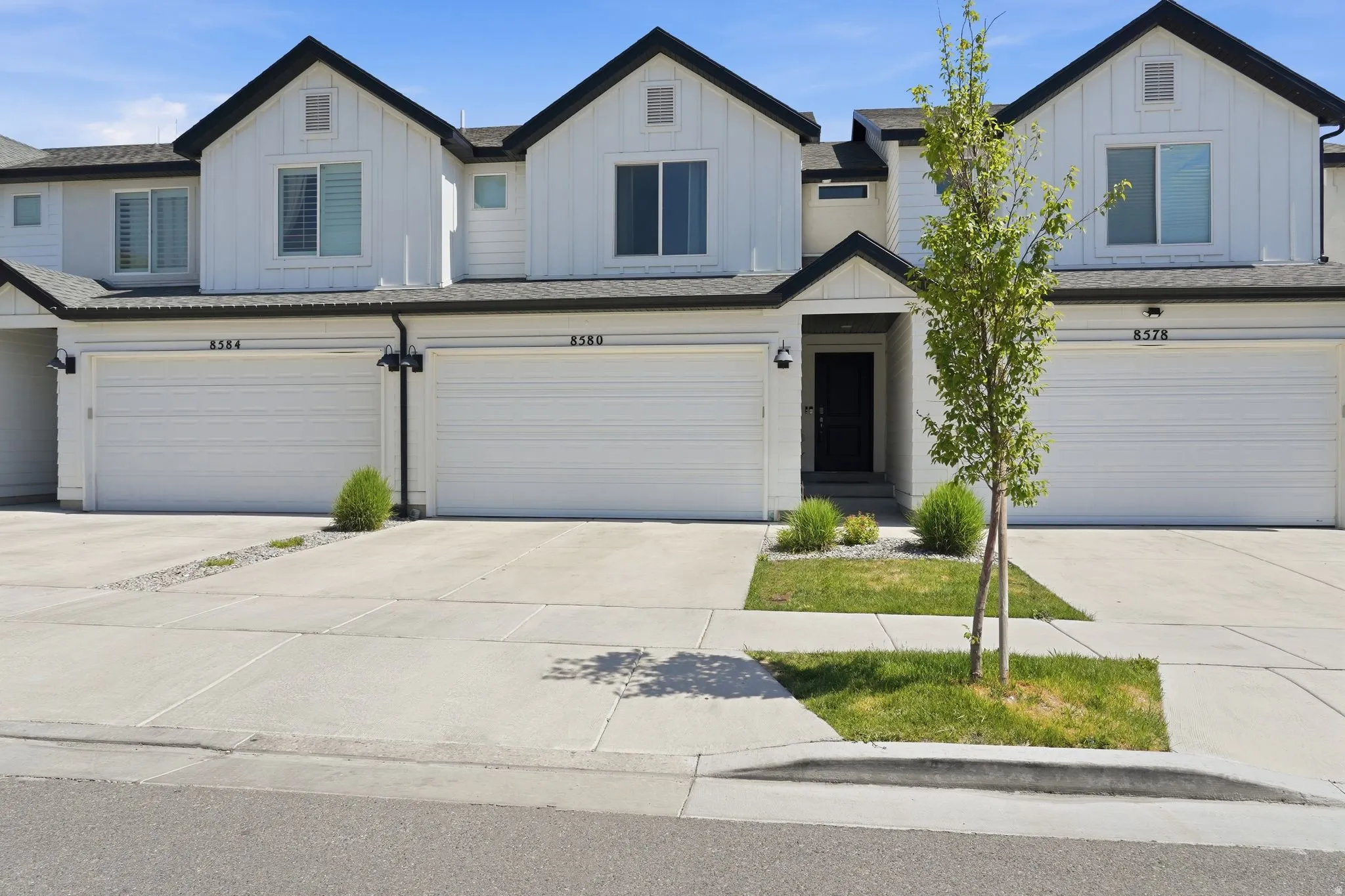 Modern townhome exterior featuring vertical white siding and dark trim
