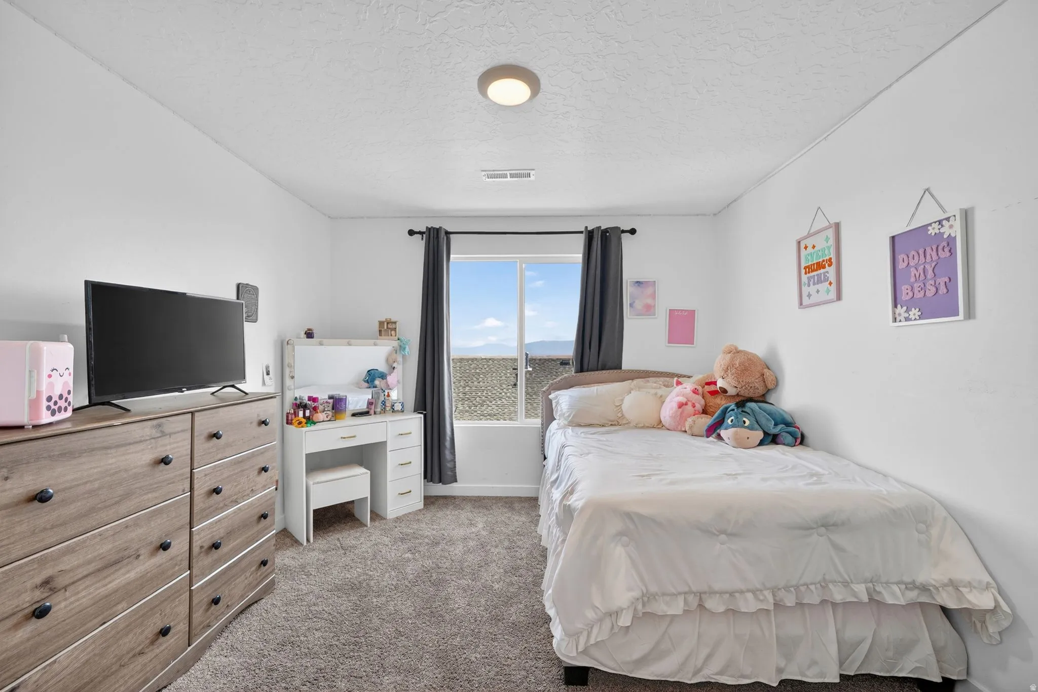 Bright room with a single window, featuring white walls, a flush-mount ceiling light, and gray carpeting