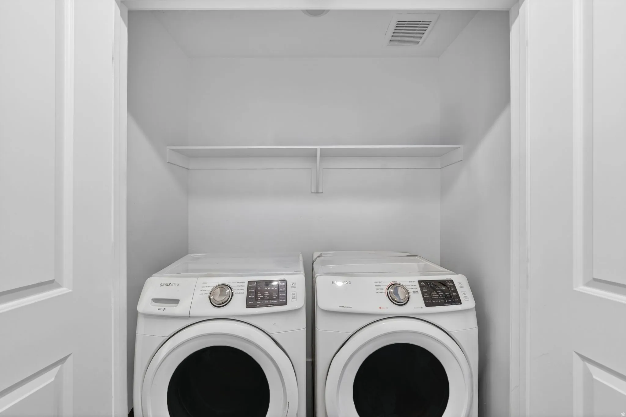 Dedicated laundry closet with white painted walls