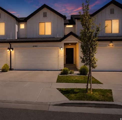 Modern farmhouse-style townhome featuring white board-and-batten siding with black trim, an attached two-car garage, and a covered entry