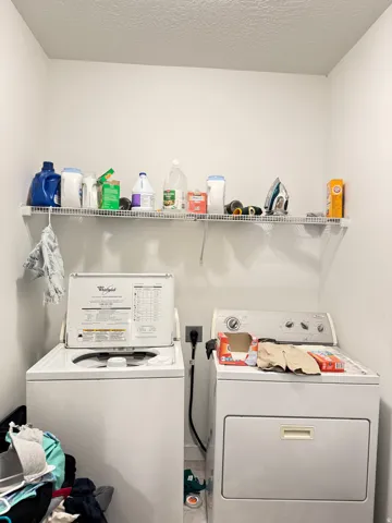 Dedicated laundry area featuring a wire storage shelf, a top-loading washing machine, and a front-loading dryer