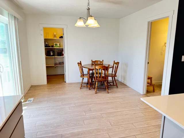 Dining area featuring light wood-finish flooring, a built-in pantry with shelving, and a modern chandelier