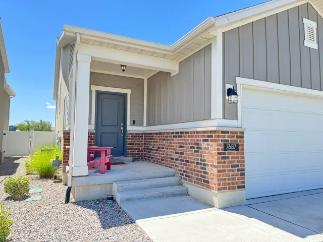 Inviting front exterior featuring a covered porch, board and batten siding, and brick accents