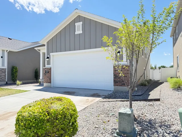 Contemporary residential exterior featuring a two-car garage, board and batten siding, brick accents, exterior lighting fixtures, and a concrete driveway