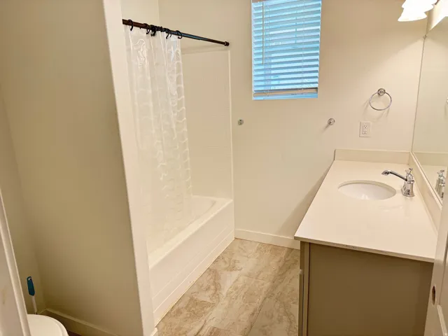 Bathroom featuring a white bathtub, a single vanity with a light-colored countertop, and a built-in sink