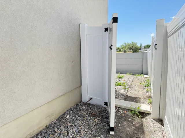 White vinyl fencing with an access gate, complementing the exterior stucco finish