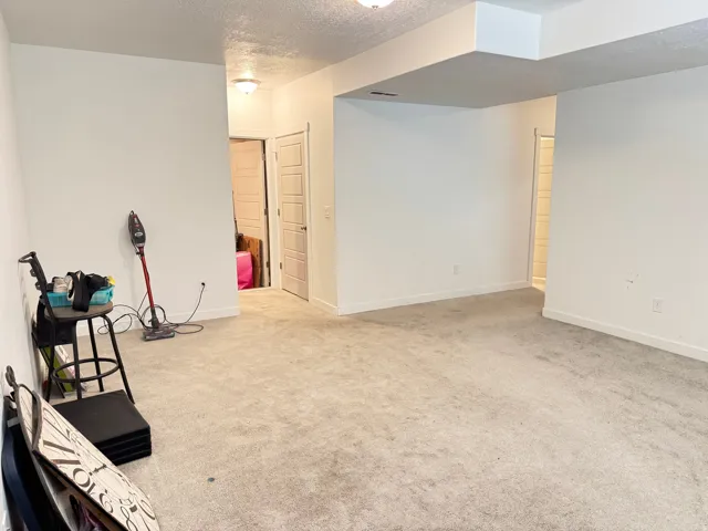 Spacious room featuring neutral carpeting, white painted walls, and recessed lighting