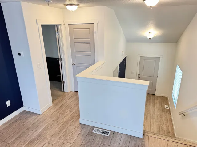 Split-level entry featuring wood-finish flooring, white trim, and a contemporary railing