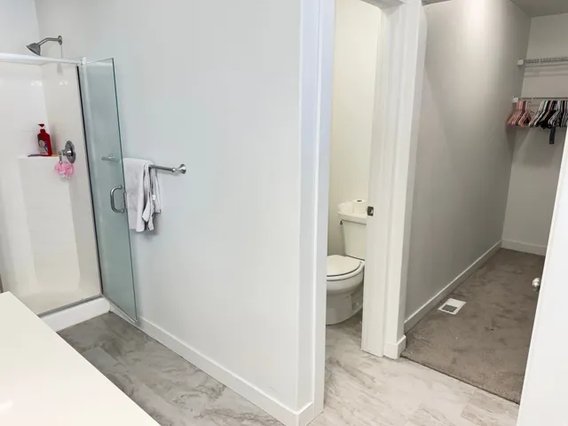 Shower enclosure with clear glass door, chrome fixtures, and a white tiled interior