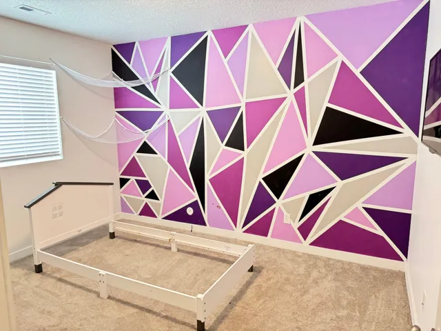 Accent wall featuring a geometric pattern in shades of purple, pink, black, and light gray