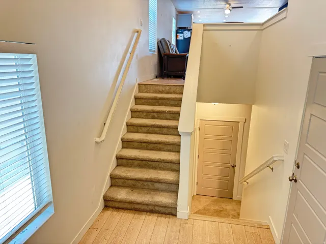 Carpeted staircase with light-toned wood-finish flooring at the base