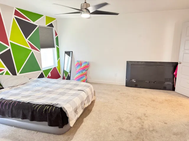 Room featuring a vibrant geometric accent wall, a window with blinds, and light-colored carpet flooring