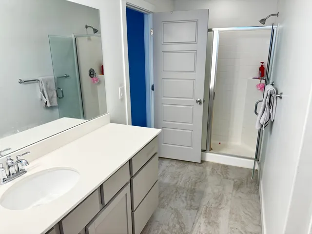 Bathroom featuring a single vanity with an oval undermount sink, a chrome faucet, and a light-toned countertop