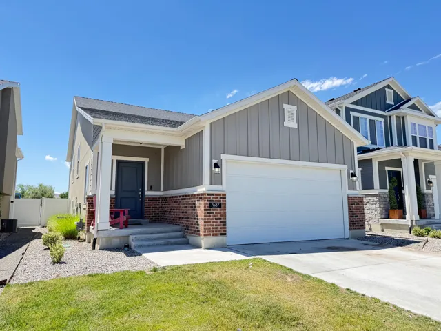 Front exterior with grey siding, brick accents, and a white garage door