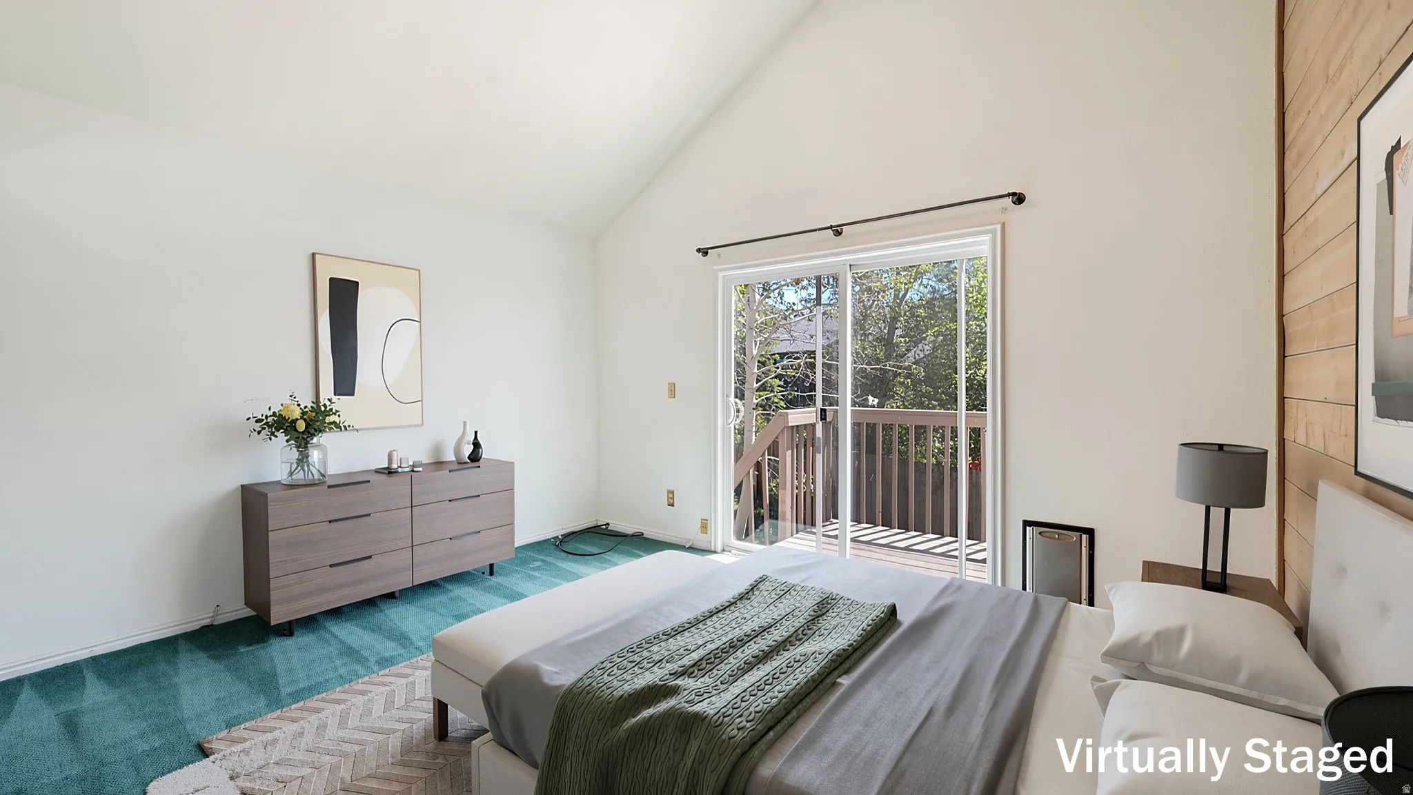 Vaulted ceilings highlight this room featuring a wooden accent wall, light-colored walls, and sliding glass doors opening to a private deck