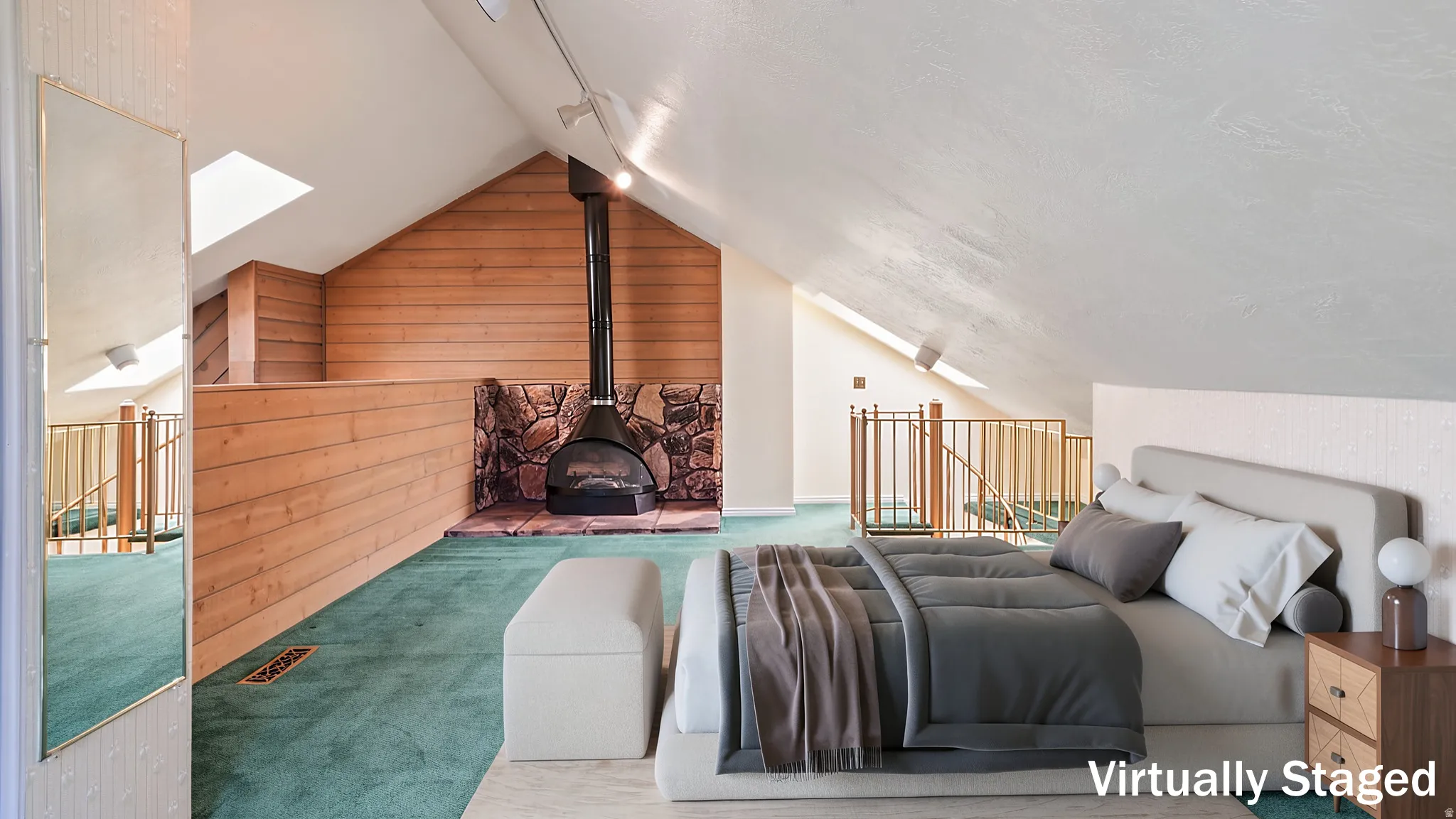 Loft space featuring a freestanding fireplace with stone surround, sloped ceilings, two skylights, wooden wall paneling, and a wood railing overlooking a lower level