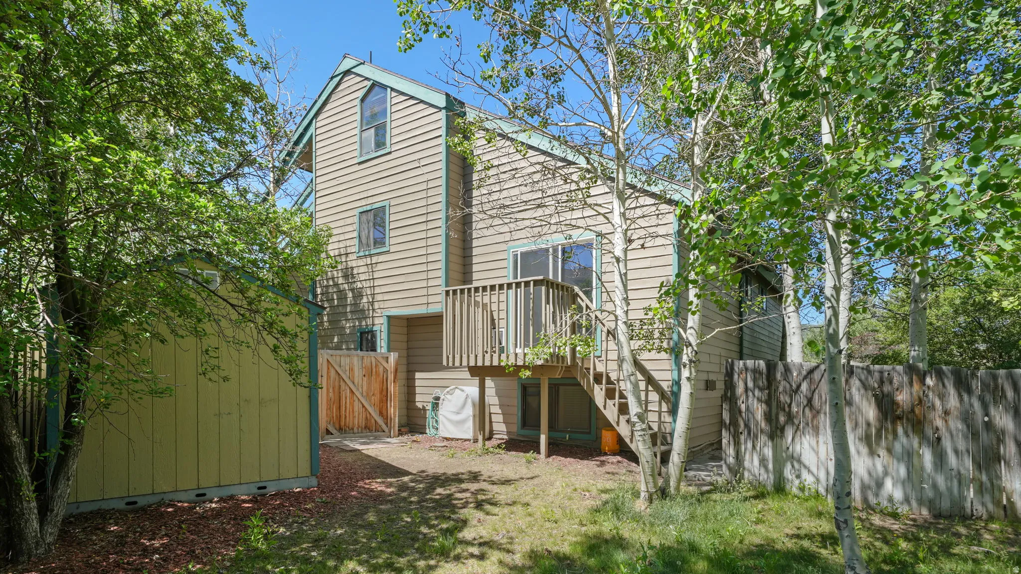 Two-story exterior with horizontal siding and accent trim, featuring a raised wooden deck with stairs