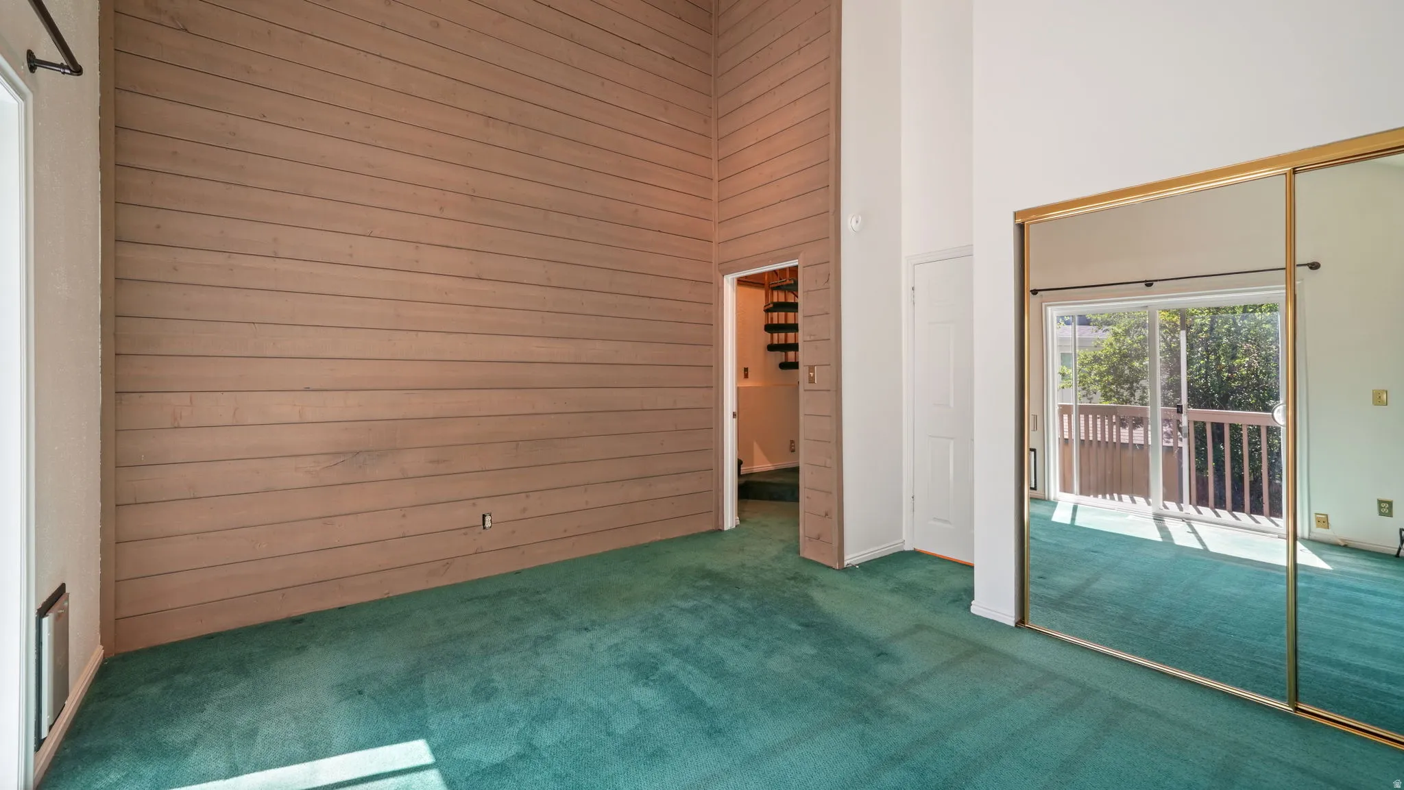Vaulted ceilings with a wood-paneled accent wall complement the plush green carpeting