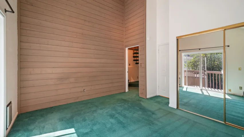 Vaulted ceilings with a wood-paneled accent wall complement the plush green carpeting