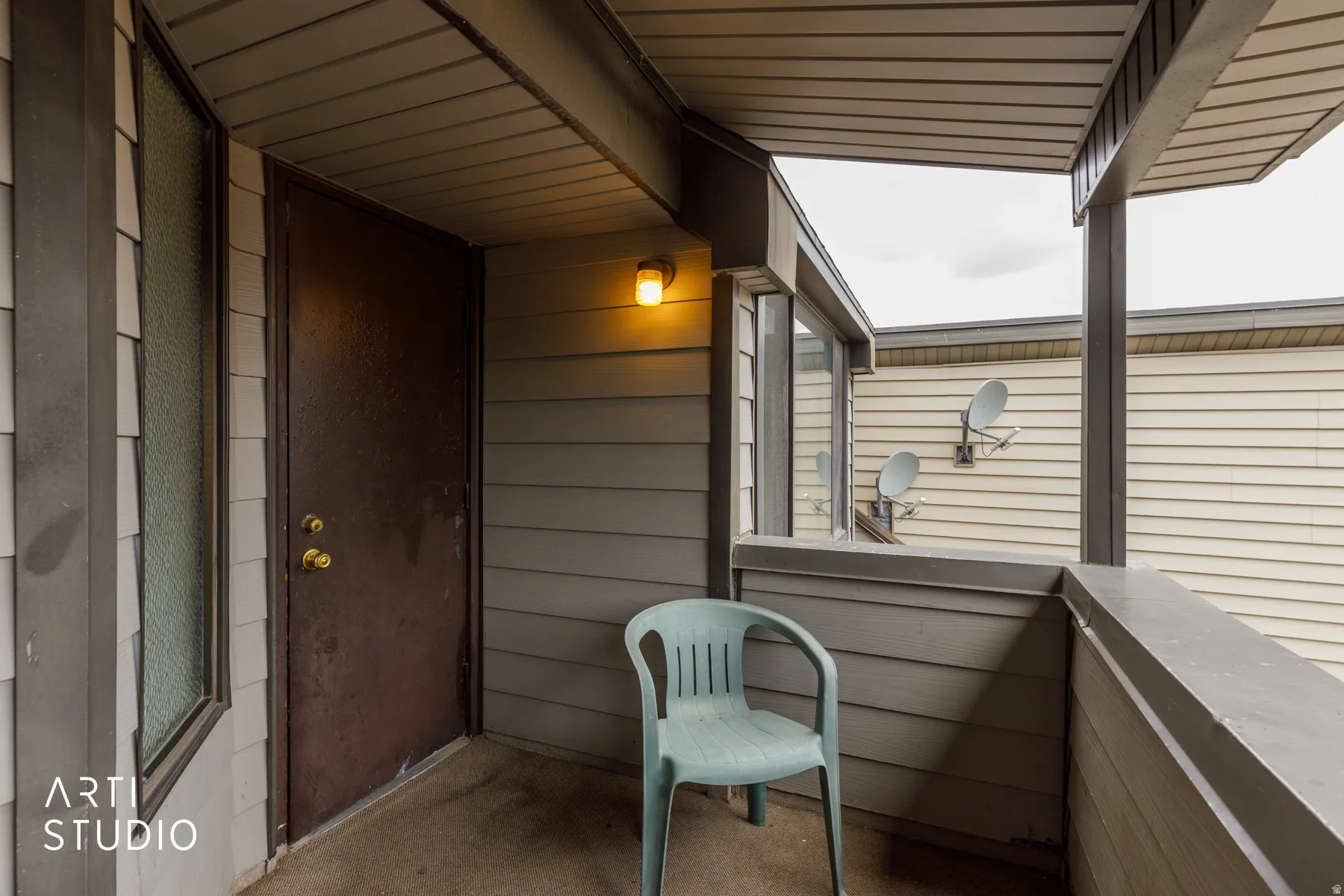 Covered exterior balcony featuring horizontal siding and a full-light entry door with brass hardware
