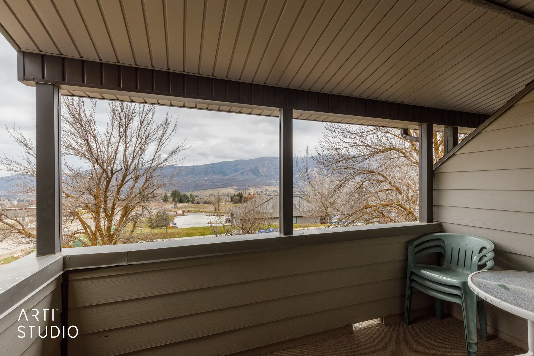 Covered balcony with a slatted ceiling, dark support beams, and mountain scenery