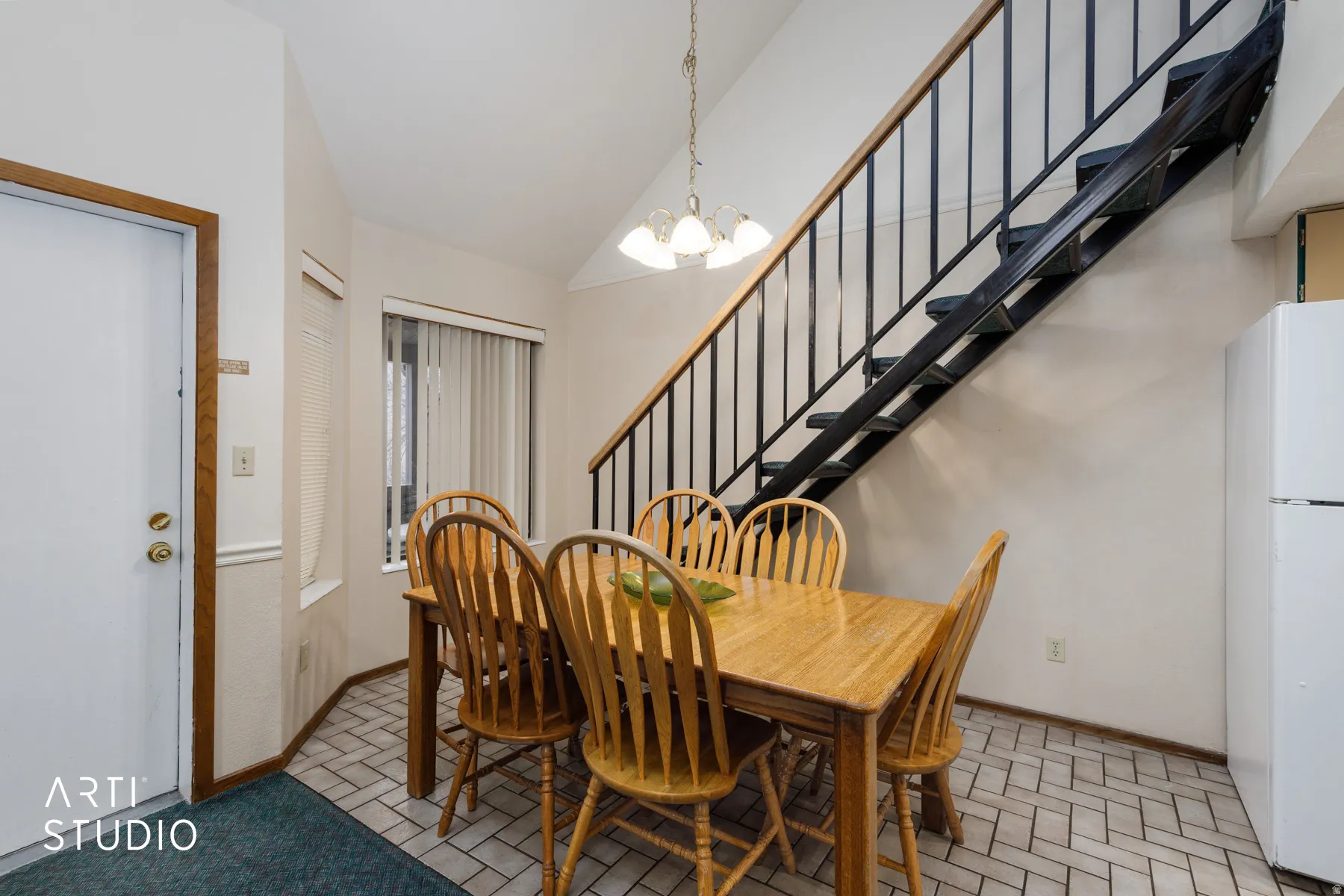 Dining area with herringbone tile flooring, a painted metal and wood-finish staircase, and an overhead chandelier light fixture