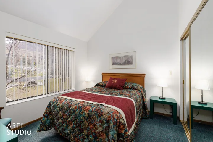 Vaulted ceilings highlight this room with a large window and mirrored closet doors