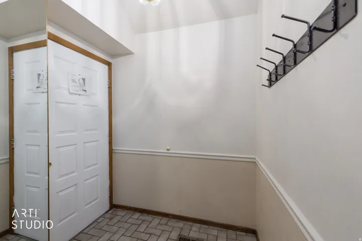 Entryway featuring a paneled door with wood-finish trim, herringbone tile flooring, wainscoting, and a wall-mounted coat rack