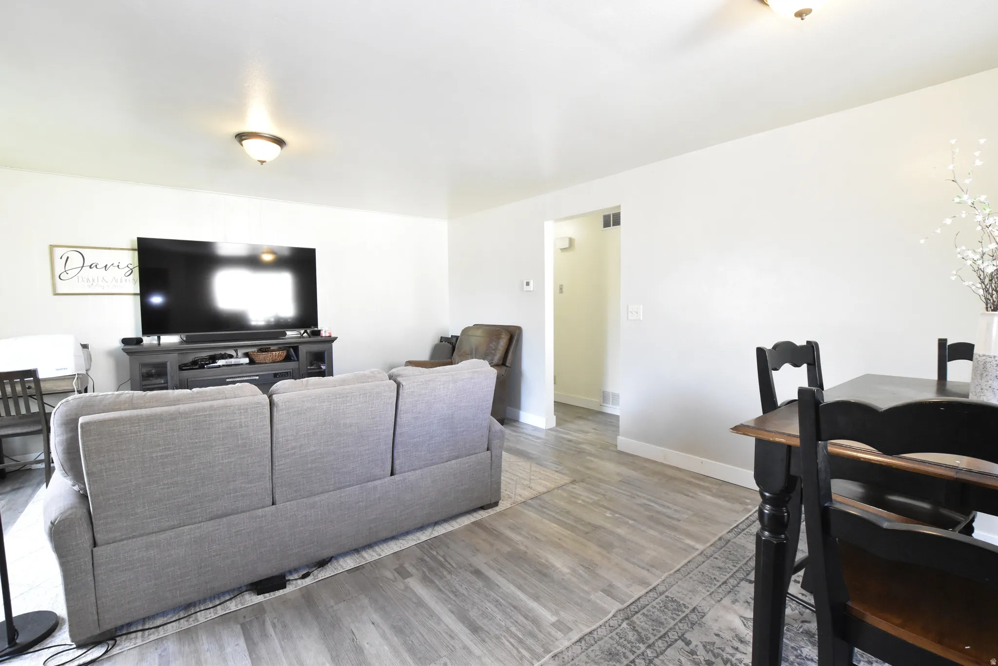 Open-concept living space featuring wood-finish flooring, recessed lighting, and crisp white walls